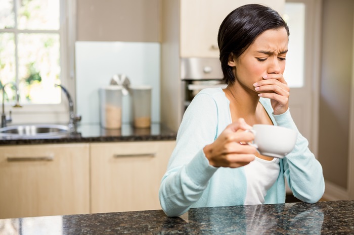 Frowning woman with toothache holding cup